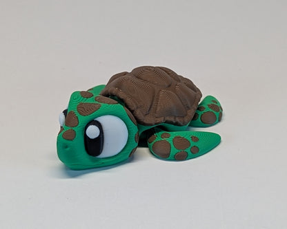 Toy turtle with a green shell and brown body on a light gray background