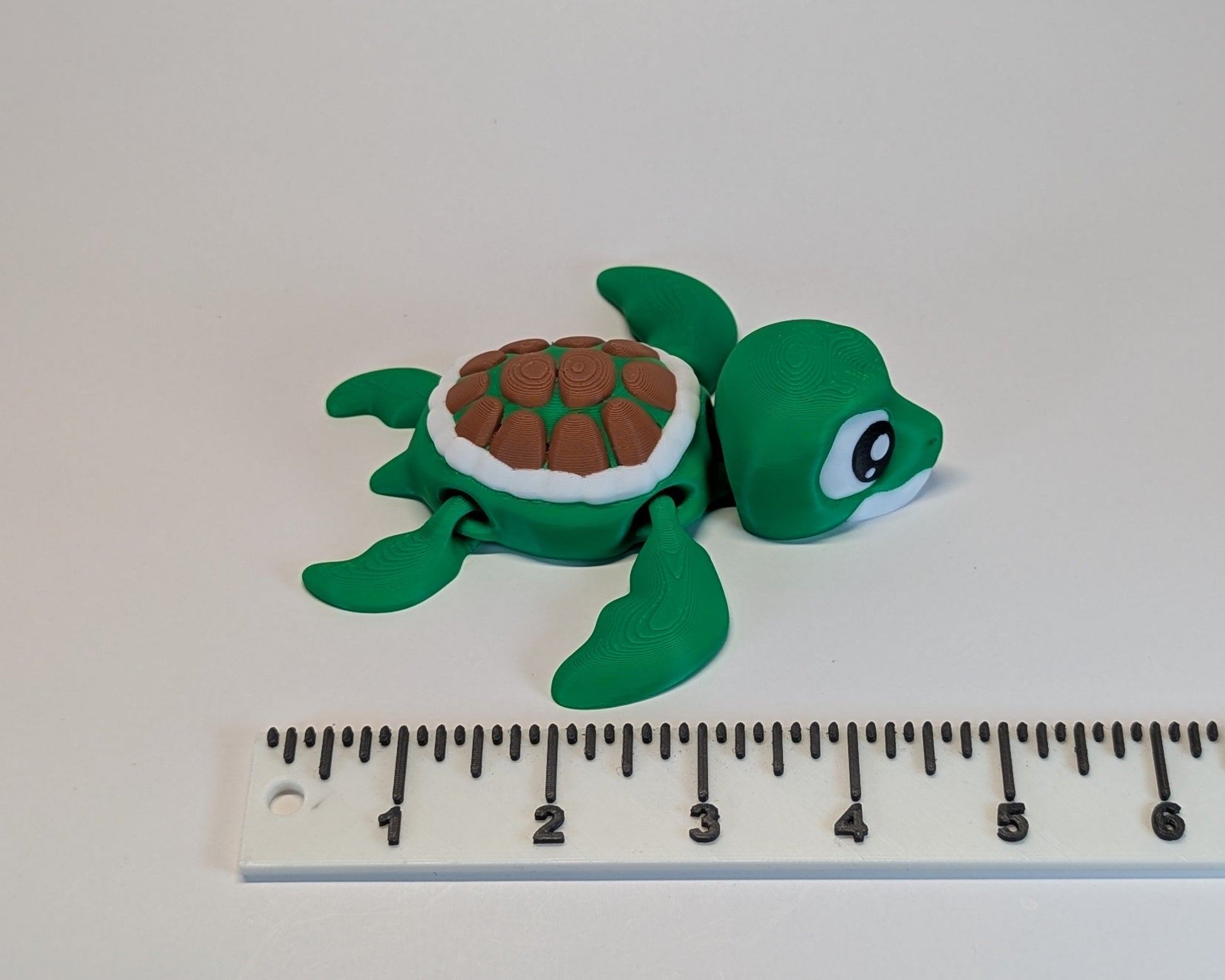 Green turtle figurine next to a ruler on a white background