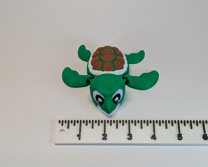 Green turtle figurine next to a ruler on a white background