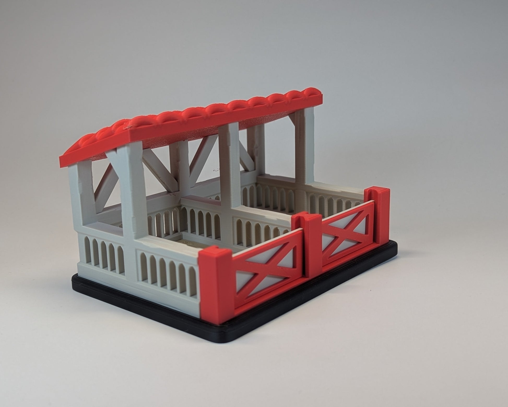Tiny Habitat Stable with red roof and fence on a gray background